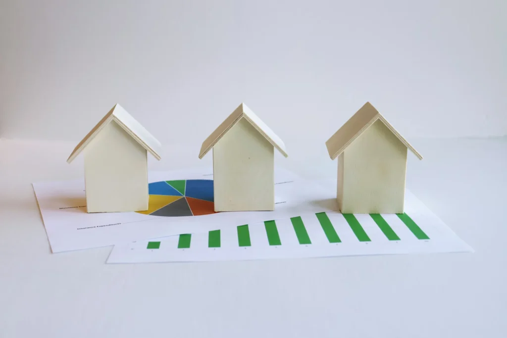 Three wooden house models placed on property management expense reports and charts